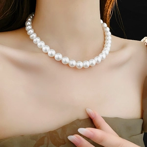 Gros plan d'un collier de perles blanches minimaliste porté pour un affichage de bijoux élégant