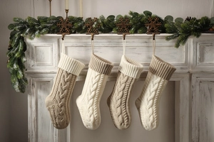 Detail of four cable knit Christmas stockings hanging from snowflake mantel hooks