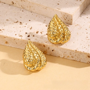 Macro detail of gold teardrop earrings with luxury hammered texture and vintage finish