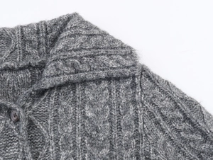 Dettaglio del colletto a risvolto e del bottone su cardigan grigio in maglia a treccia