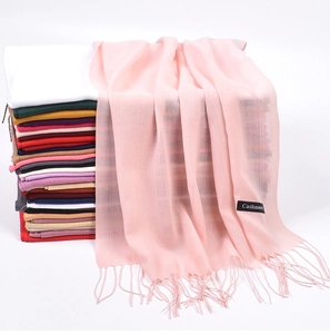 Close-up of pink cashmere scarf with tassels and multicolor stack of scarves