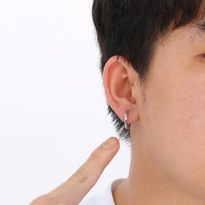 Close-up of a silver stainless steel Mobius hoop earring on male ear with sharp detail