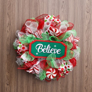 Christmas wreath with red and green mesh on a wooden background for holiday wall decor
