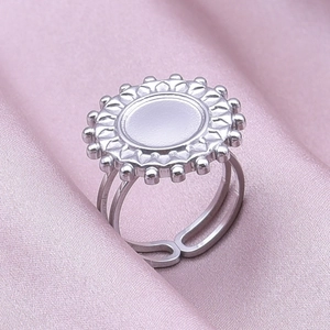 Detailed macro view of silver stainless steel sunflower ring on purple silk fabric