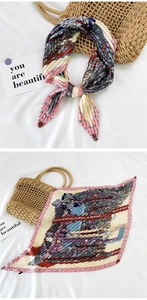 Detail of pleated silk scarf with vintage geometric prints on a white fabric background
