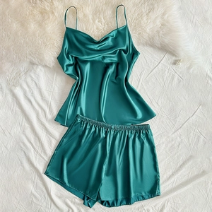 Dark green satin pajama set with camisole and elastic shorts on soft white background