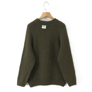 Close-up of fluffy dark green knit sweater texture with round neck and designer label