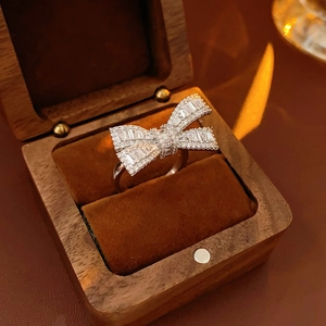 Macro detail of silver bow ring with zircon stones in a wooden jewelry box