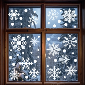 Detail of white snowflake window clings on glass with a snowy forest background