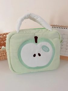 Close-up of quilted light green travel cosmetic bag with apple embroidery and top handle