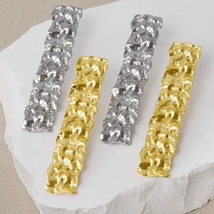 Macro view of textured rectangular earrings in gold and silver with hammer texture finish