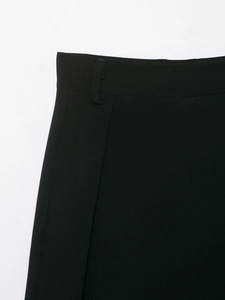 Detail of high-waist black trousers featuring belt loops and precision tailoring stitching