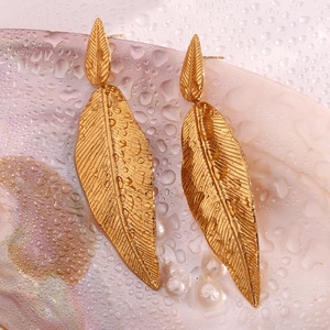 Close-up of 18K gold leaf earrings with intricate vein details on shell background