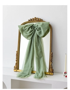 Large bean green sheer tulle bow hanging on a vintage gold mirror for holiday decoration