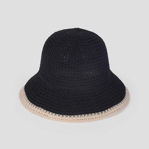 Dettaglio del cappello da sole in maglia nera con bordo a contrasto beige e texture traspirante