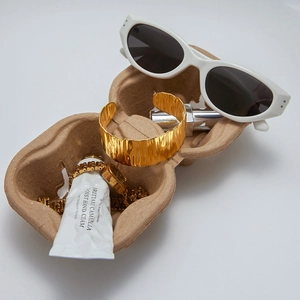 Detailed close-up of golden wide cuff bracelet with hammer texture on a molded pulp tray