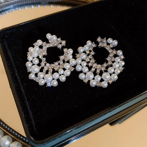 Boucles d'oreilles géométriques en perles et strass sur un présentoir en velours noir