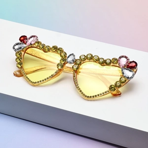 Cat eye sunglasses for women with yellow rhinestones and pear-shaped crystals on pink background