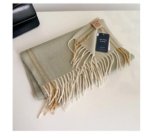 Detail shot of light green 100% wool scarf featuring orange stripes and fringe edges