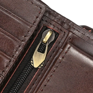 Macro shot of dark brown leather texture with bronze metal zipper and red stitching