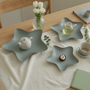Minimalist star-shaped matte gray-green iron trays on a textured white tablecloth