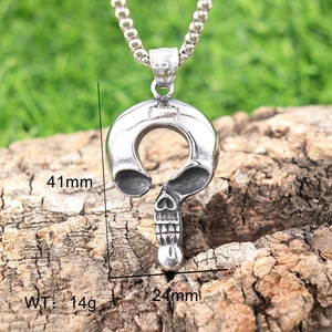 Détail d'un pendentif tête de mort vintage en acier avec motif cœur et chaîne