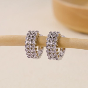 Macro shot of silver hoop earrings with three rows of sparkling cubic zirconia stones