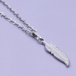 Detailed macro view of the finely textured silver feather pendant on a steel chain