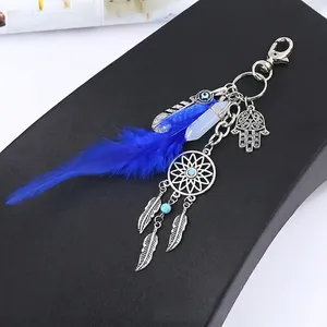 Detailed view of the Hamsa Hand and dreamcatcher charms on blue feather keychain