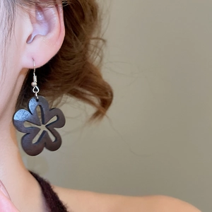 Vue détaillée d'une boucle d'oreille vintage en bois sombre avec motifs fleurs ajourés