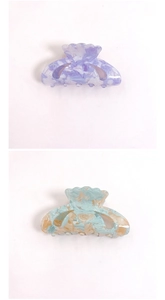 Detail of shell-shaped acrylic hair claws with purple and blue marble patterns