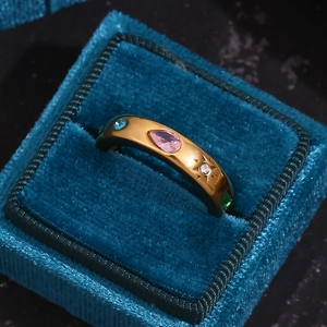 Close-up of gold ring with pink pear-cut and multicolor zircons in a blue velvet box