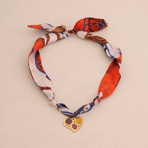 Silk scarf necklace with gold heart pendant featuring orange blue patterns on beige background