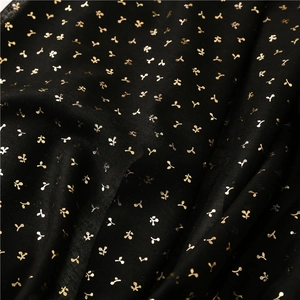 Close-up of black cotton-linen scarf fabric with gold floral pattern and soft texture