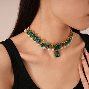 Detail of layered gold necklace with emerald green crystals and elegant white pearls