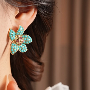 Detailed close-up of vintage flower earrings featuring blue petals and red crystal center