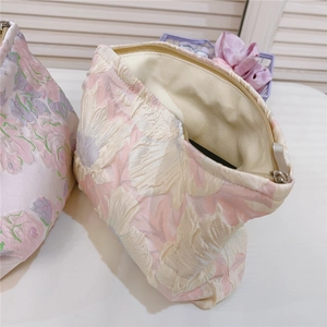 Detailed close-up of pink floral jacquard fabric cosmetic bag with beige lining