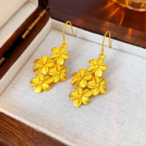 Gros plan de boucles d'oreilles fleurs plaquées or 18K avec texture métallique mate