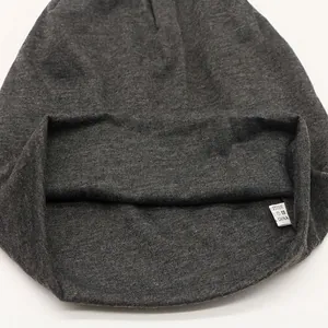 Unisex dark grey knit beanie showing internal stitching and fabric care label details
