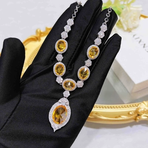 Macro detail of luxury water-drop pendant with oval yellow gemstone and white zircons
