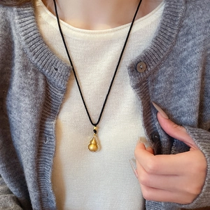Primo piano di una collana a forma di zucca dorata con zirconi indossata dal modello