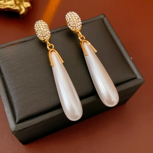 Macro view of long waterdrop pearl earrings with sparkling rhinestones on jewelry box