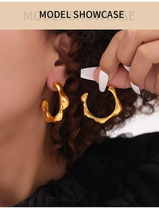 Model wearing gold irregular C-shape hoop earrings with molten lava texture finish