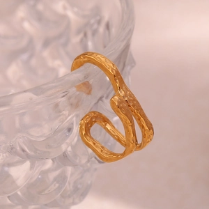 Detail of 18K gold-plated irregular textured ring hung on relief glass with pink background