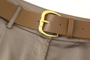 Detail shot of brown leather belt with gold metal buckle on dark coffee wide leg pants