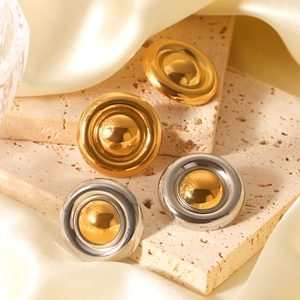 Macro detail of round 18K gold-plated earrings on beige travertine with silk fabric