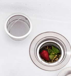 Detail of stainless steel sink strainer with handle filtering food waste in a kitchen sink