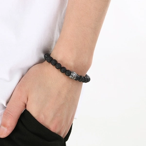 Close-up of black volcanic stone bracelet with a silver geometric bead on a male wrist