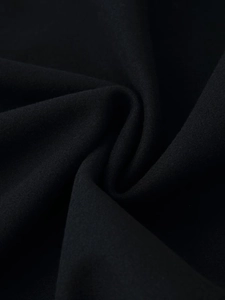 Gros plan du tissu du manteau en laine noir montrant une texture brossée et épaisse