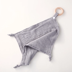 Detalle de la manta de apego de gasa de algodón gris con aro de madera natural